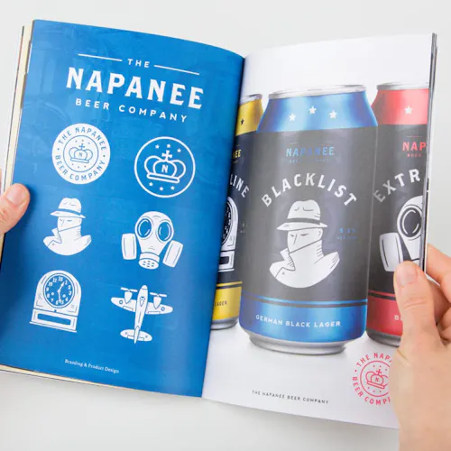 Two hands holding open a portfolio to beer cans with custom illustrations on them.