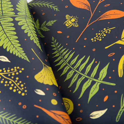 A closeup of two pieces of printed paper with a navy blue background and leaves in green, orange and yellow.