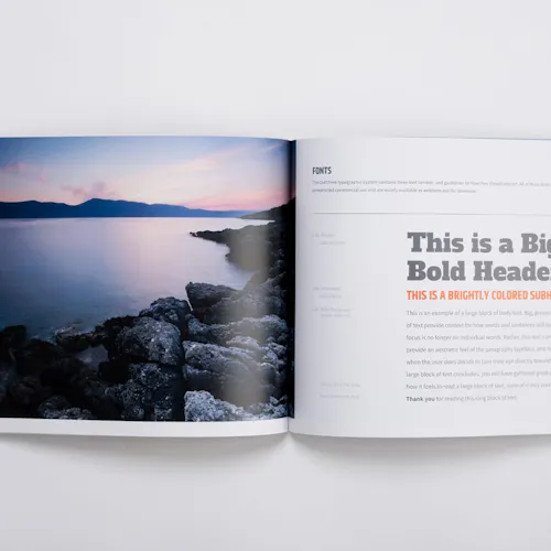 A brand manual laying open to a lake with a rocky shoreline and information about fonts.