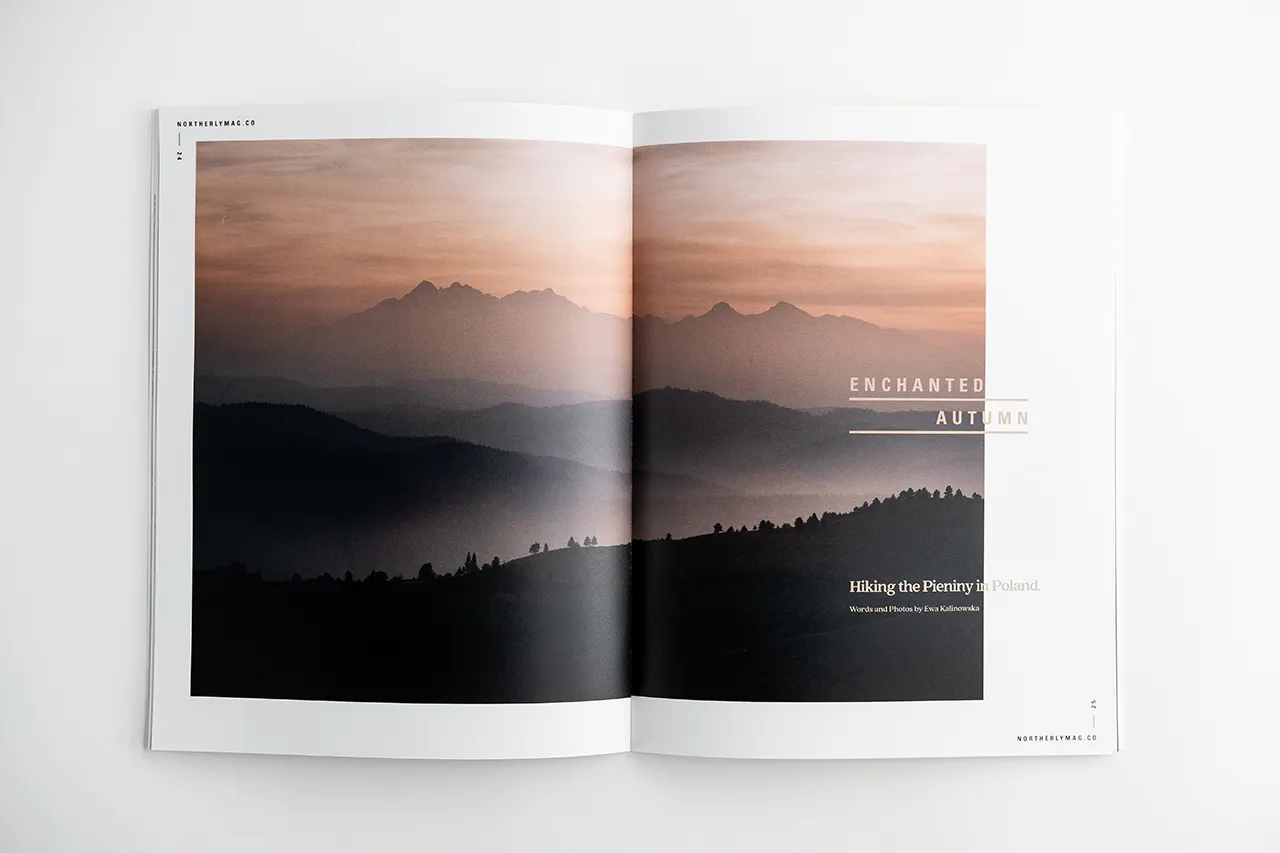 Two hands holding open a visual journal to a landscape of foggy, tree-covered mountains.