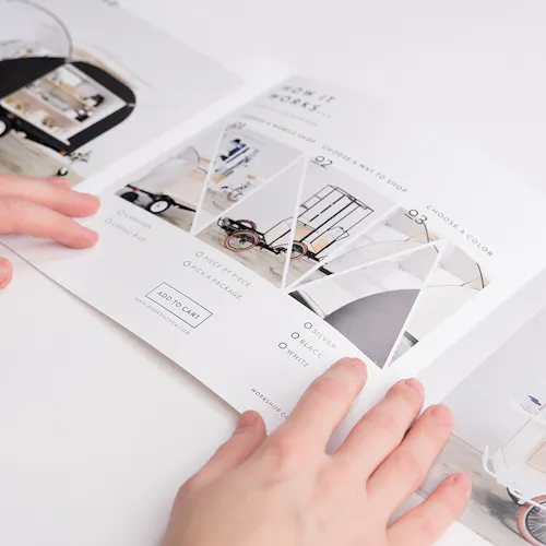 Two hands holding open a tri-fold square brochure with images and details of mobile retails shops.