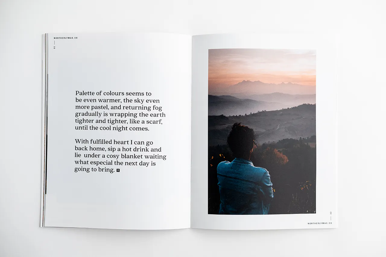 Two hands holding open a visual journal to an image of a person overlooking a foggy mountain range.