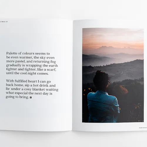 Two hands holding open a visual journal to an image of a person overlooking a foggy mountain range.