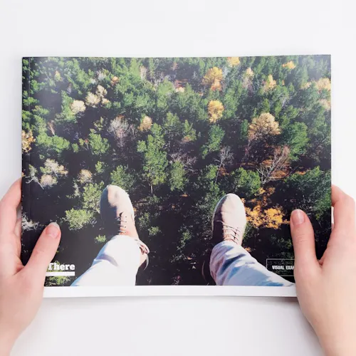 Two hands holding a custom brand manual printed with a forest scene from above on the cover.