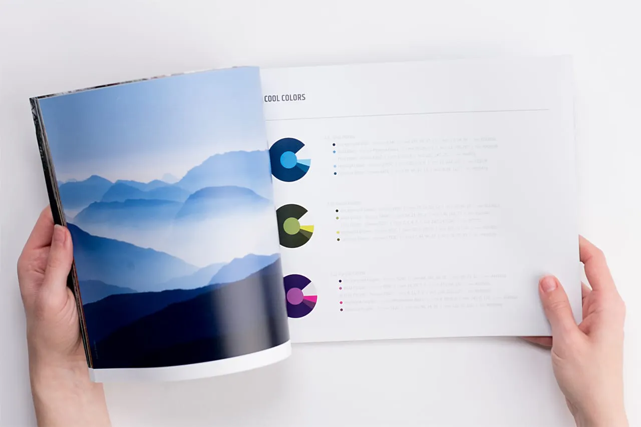A brand manual laying open to a blue, foggy mountain scene and information about color.