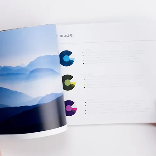 A brand manual laying open to a blue, foggy mountain scene and information about color.