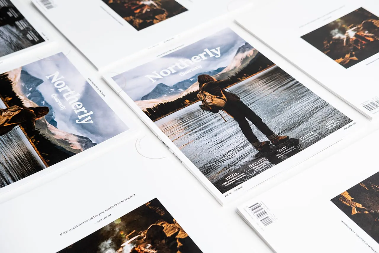 Northerly visual journals lined up in rows with a person wearing a backpack on the cover.
