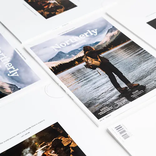 Northerly visual journals lined up in rows with a person wearing a backpack on the cover.