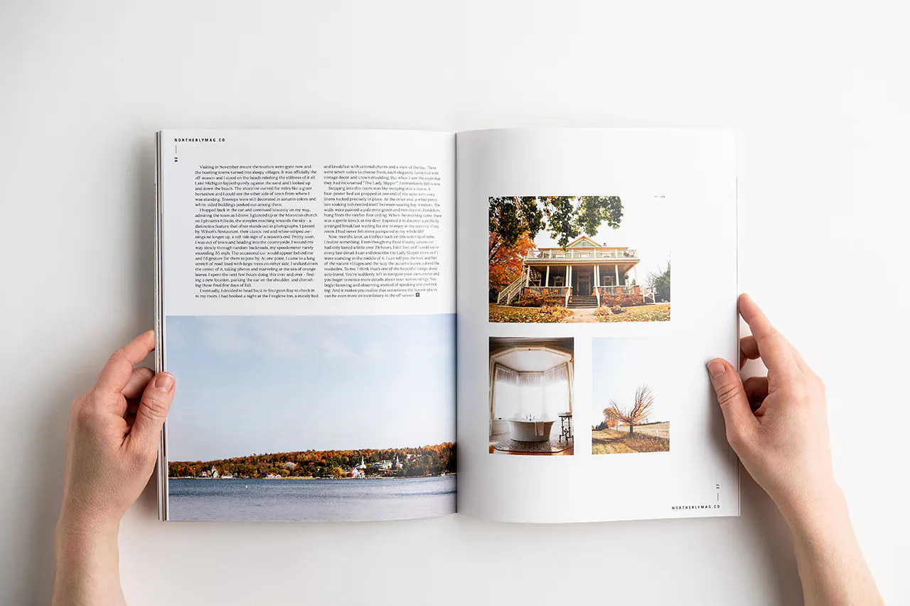 Two hands holding open a visual journal to images of a house, bathtub, autumn tree and shoreline.