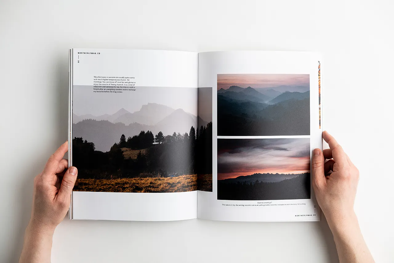 Two hands holding open a visual journal to images of foggy mountain landscapes.