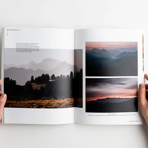 Two hands holding open a visual journal to images of foggy mountain landscapes.