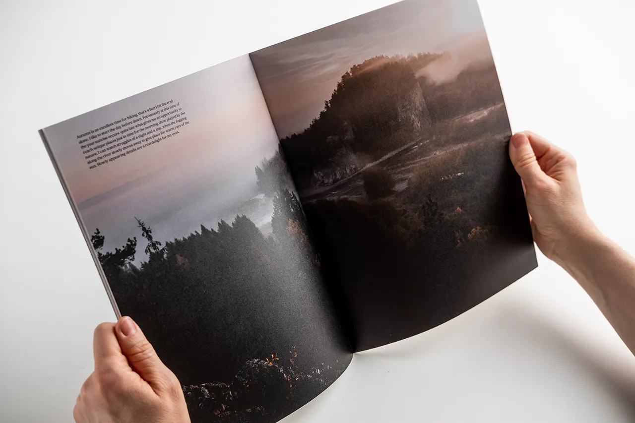 Two hands holding open a visual journal to images of a foggy mountain and lake scene.