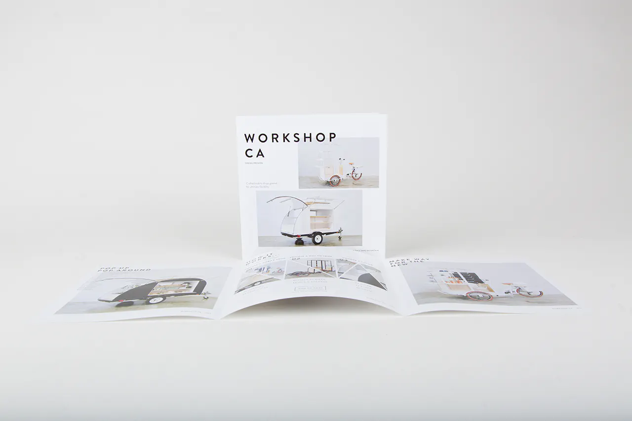 A square marketing brochure standing next to an unfolded brochure printed with Workshop CA.