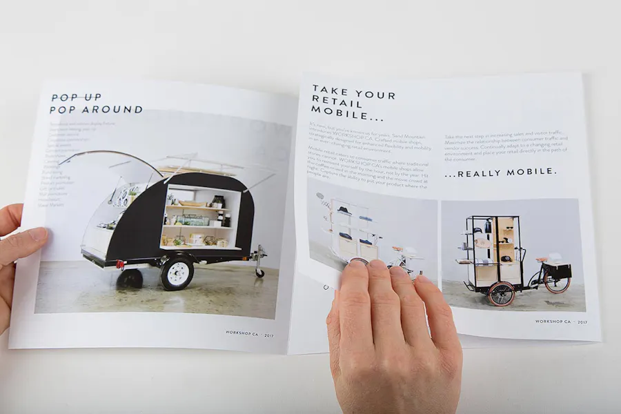 Two hands unfolding a custom tri-fold brochure with images of mobile retail carts.