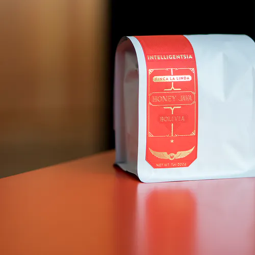 A white bag of Intelligentsia coffee with a red and gold label sitting on a table.