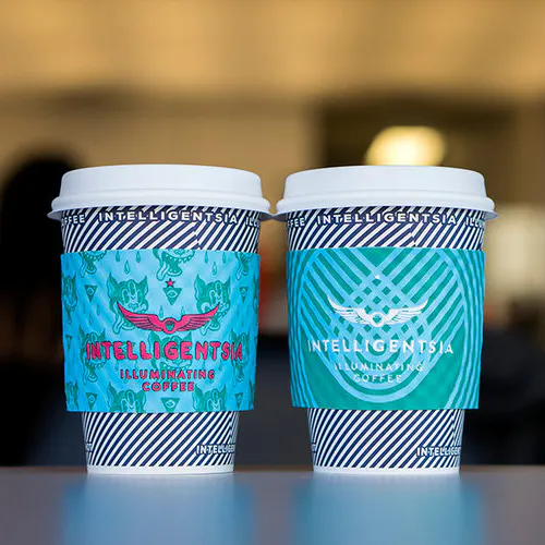 Two coffee cups with a navy blue striped design and coffee sleeves printed with Intelligentsia.