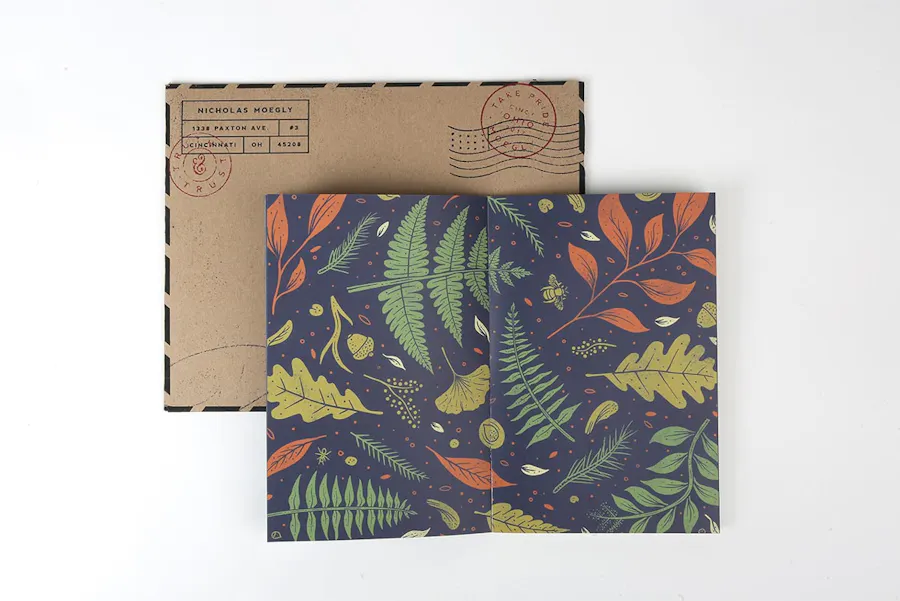 A custom photography portfolio printed with a foliage design on the front with a matching envelope behind it.