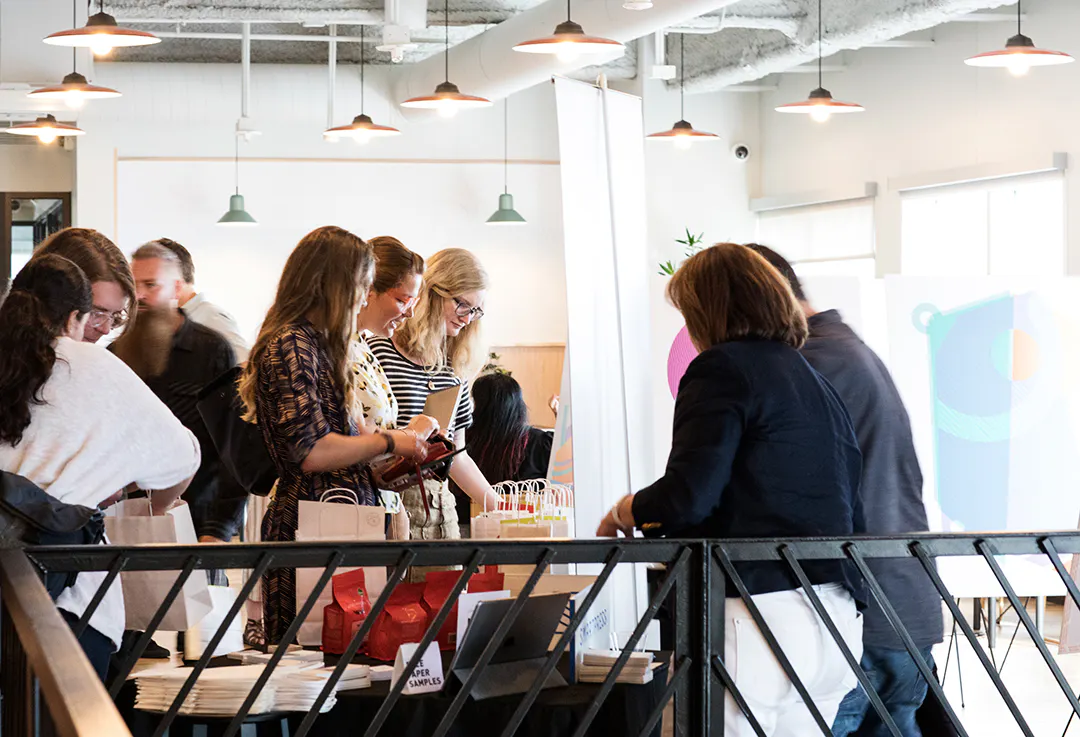 People standing in front of a table with merchandise in small paper bags with handles.