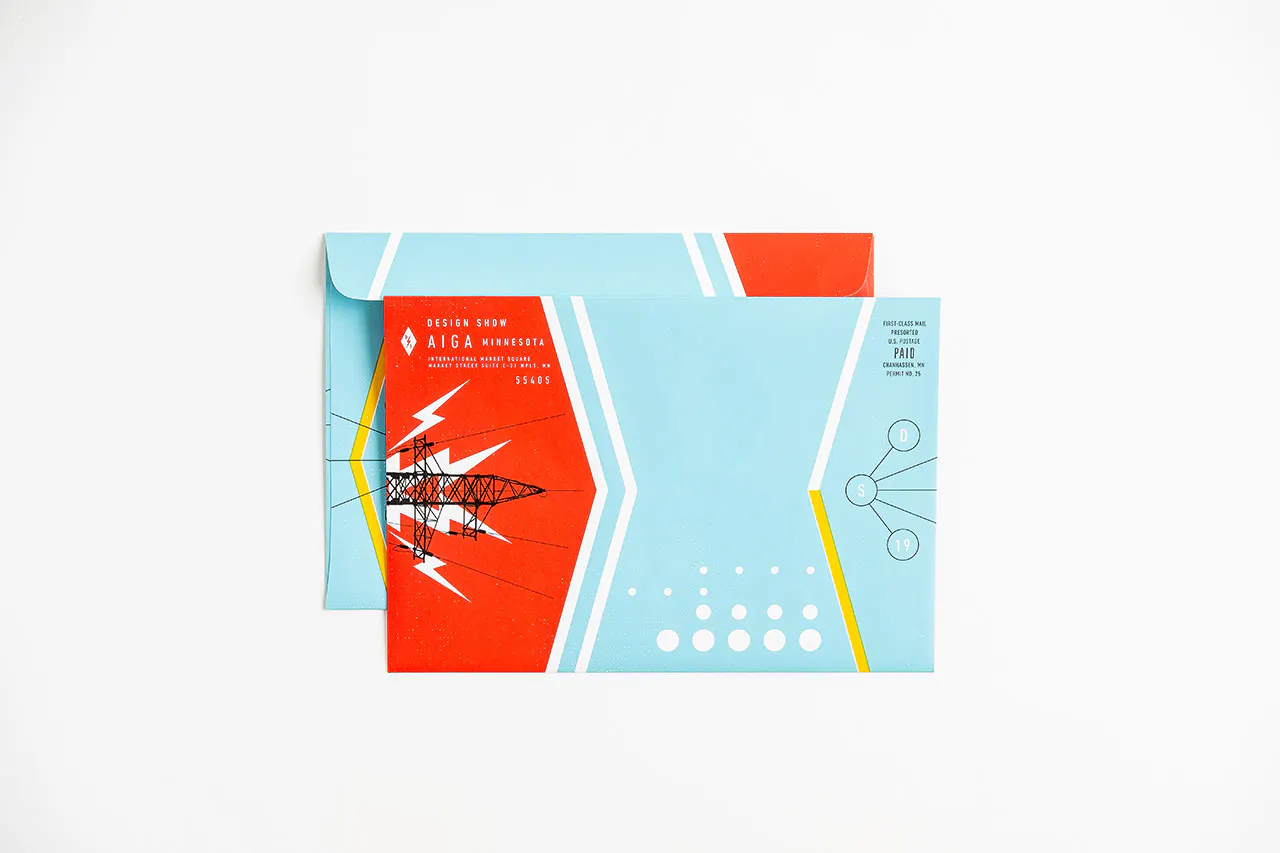 A direct mailer envelope printed with a blue, red and white design and Design Show AIGA Minnesota in the corner.