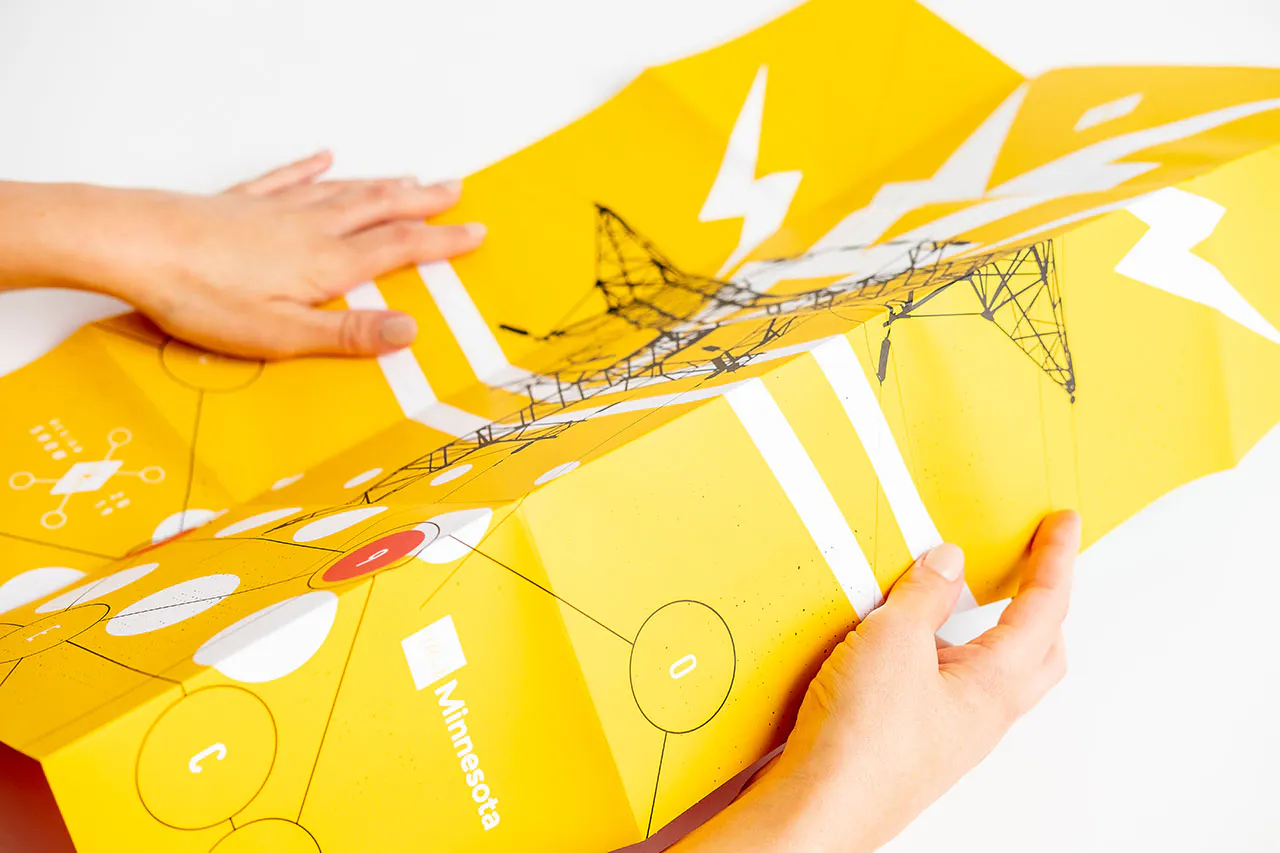 Two hands unfolding a piece of direct mail with a yellow, black and white design.