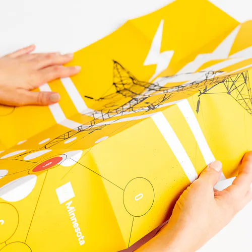 Two hands unfolding a piece of direct mail with a yellow, black and white design.