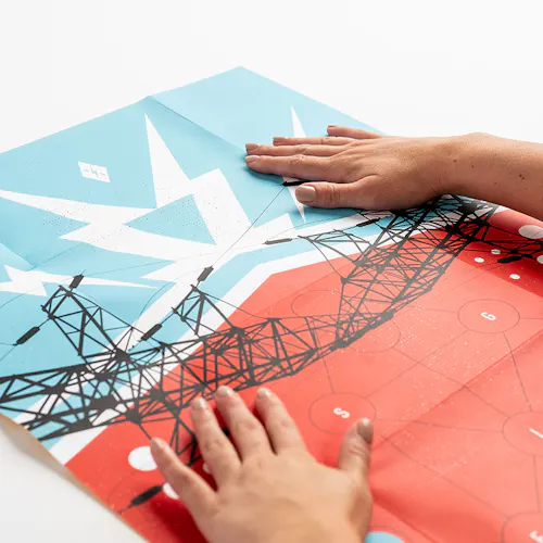 Two hands laying on an unfolded direct mail poster with a blue, red, black and white design.