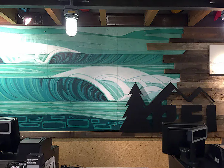Custom wall art with a waves-inspired design shades of green in an REI store.