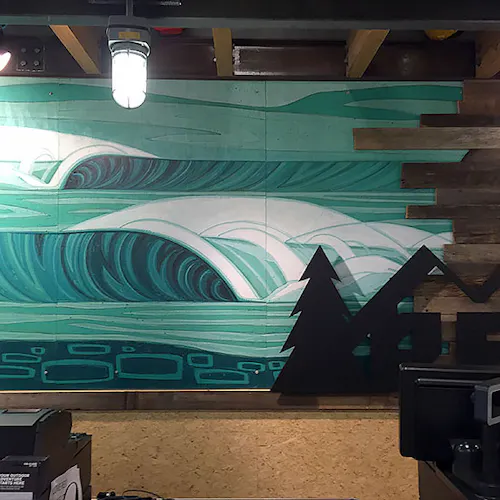 Custom wall art with a waves-inspired design shades of green in an REI store.