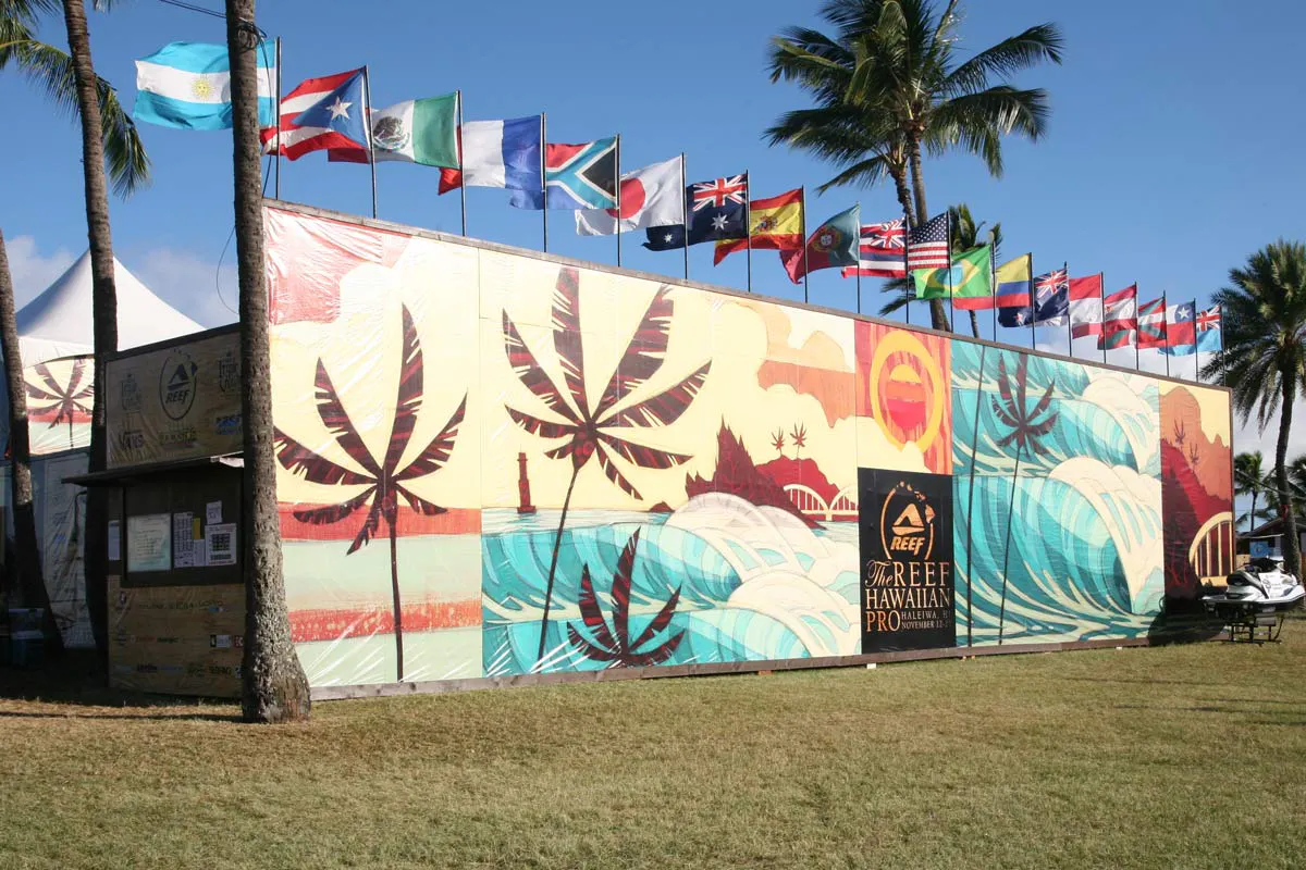 A custom banner printed with palm trees and a beach-inspired scene with flags from different countries waving above it.