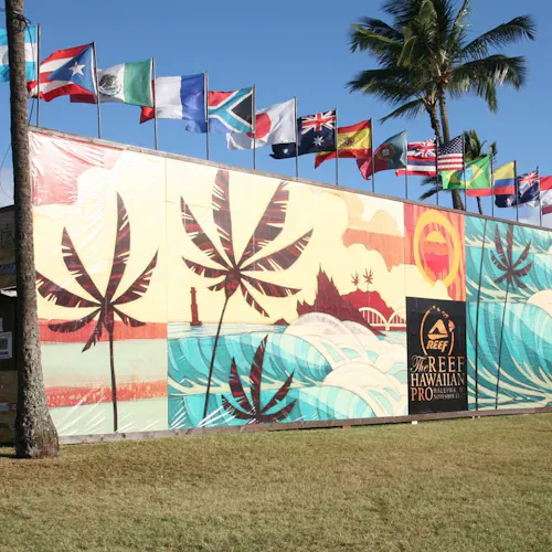 A custom banner printed with palm trees and a beach-inspired scene with flags from different countries waving above it.