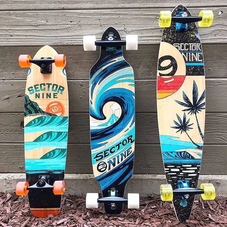 Three skateboards lined up in a row with custom beach-inspired artwork on the bottoms.