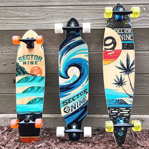 Three skateboards lined up in a row with custom beach-inspired artwork on the bottoms.