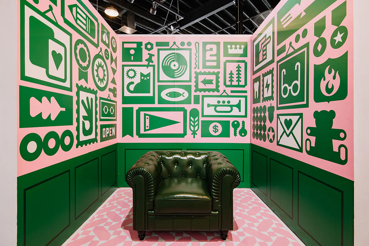 A green club chair in the middle of a display with custom wall decals printed with pink and green designs surrounding it.