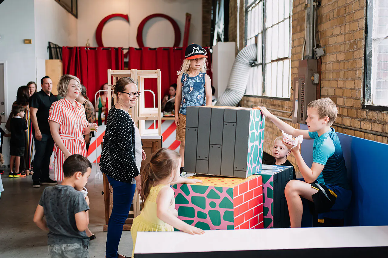 A group of young children playing with large blocks with custom printed decals on the sides.