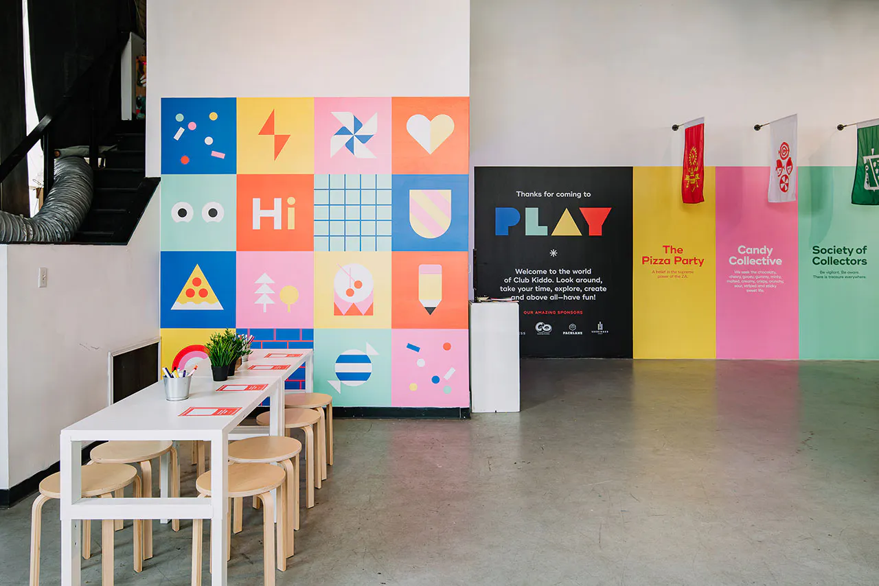 The Club Kiddo PLAY space with a table and chairs for kids and colorful wall decals all around.