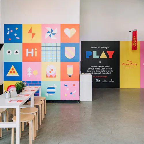 The Club Kiddo PLAY space with a table and chairs for kids and colorful wall decals all around.