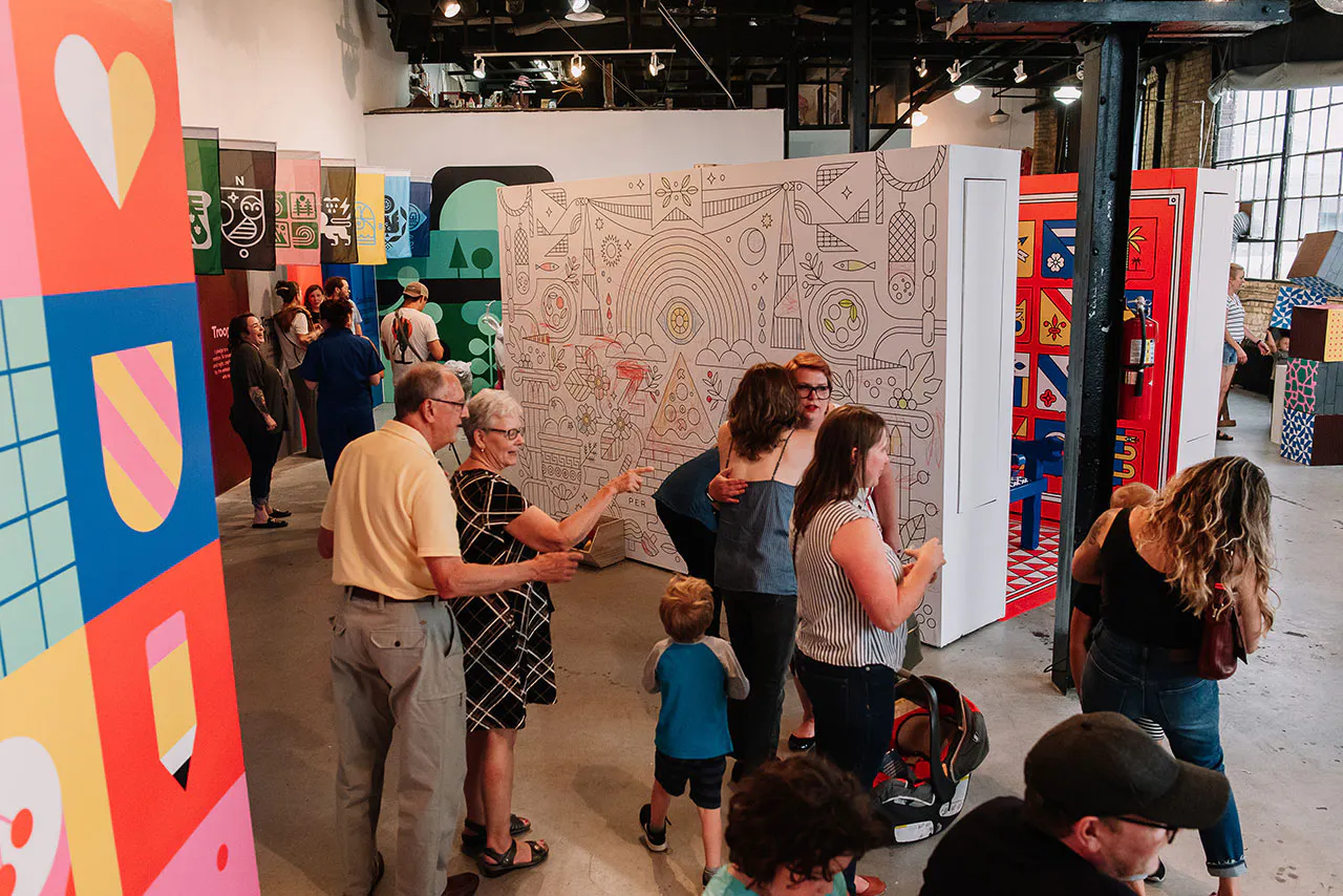 Adults and children walking through Club Kiddo with large displays covered in bright wall decals.