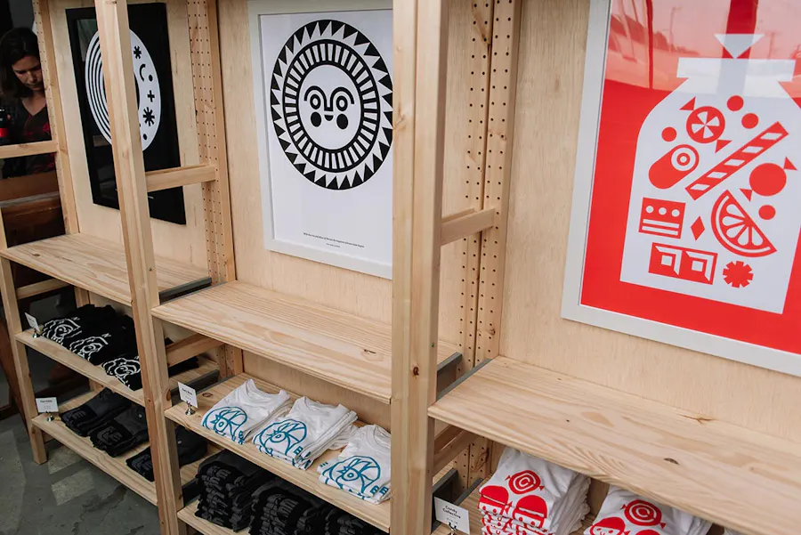 A Club Kiddo display rack with branded merch, posters and apparel.