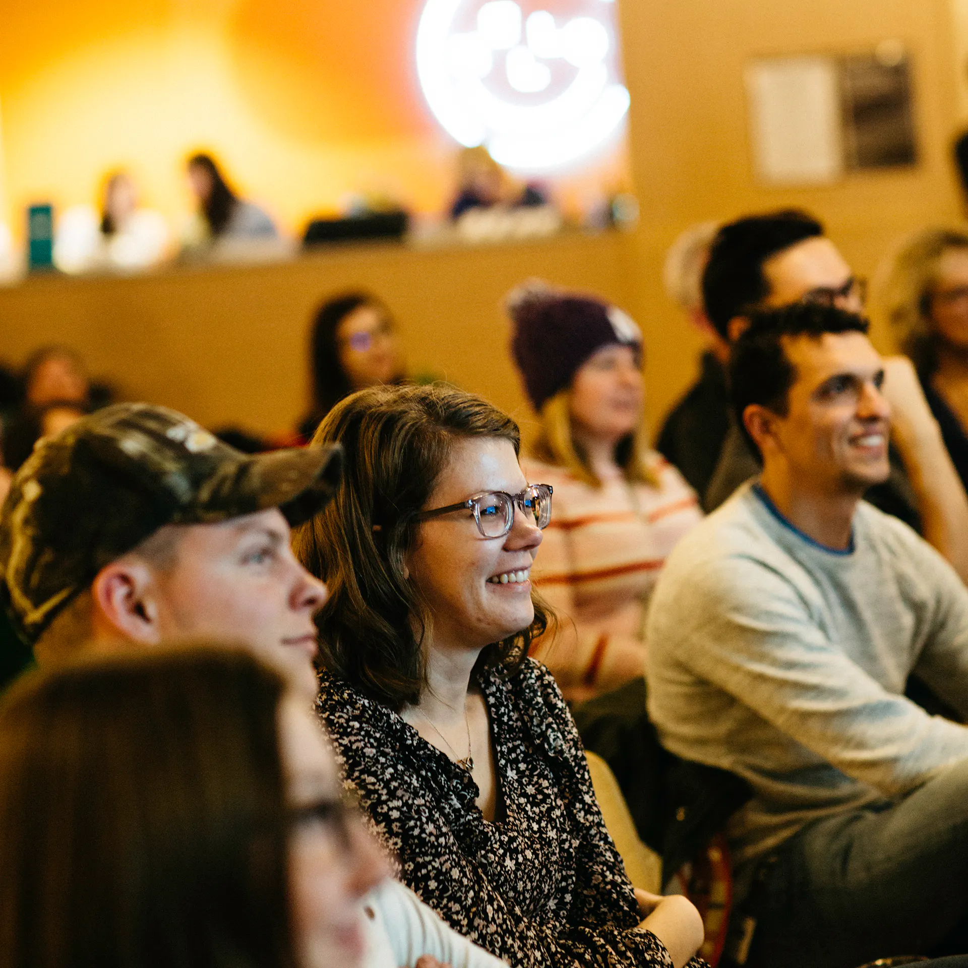 An audience of smiling people sitting and listening to a presentation.