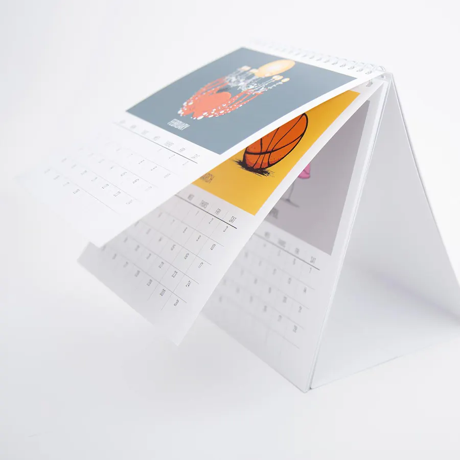 A desk calendar printed with custom artwork on each page, including a basketball and a chandelier.