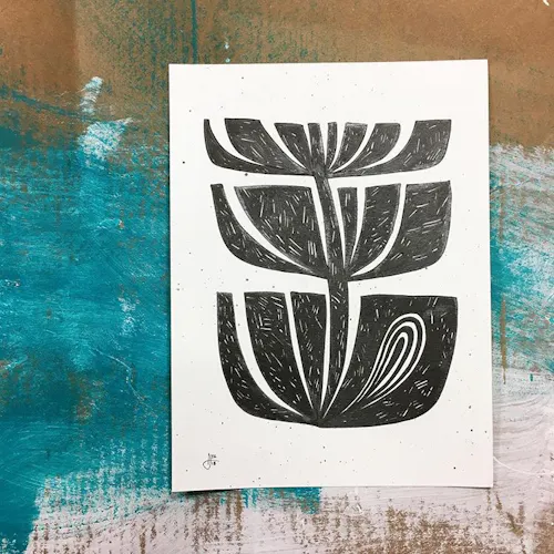 A custom art print with a Hawaiian-inspired design laying on top of a wooden slab with paint on it.