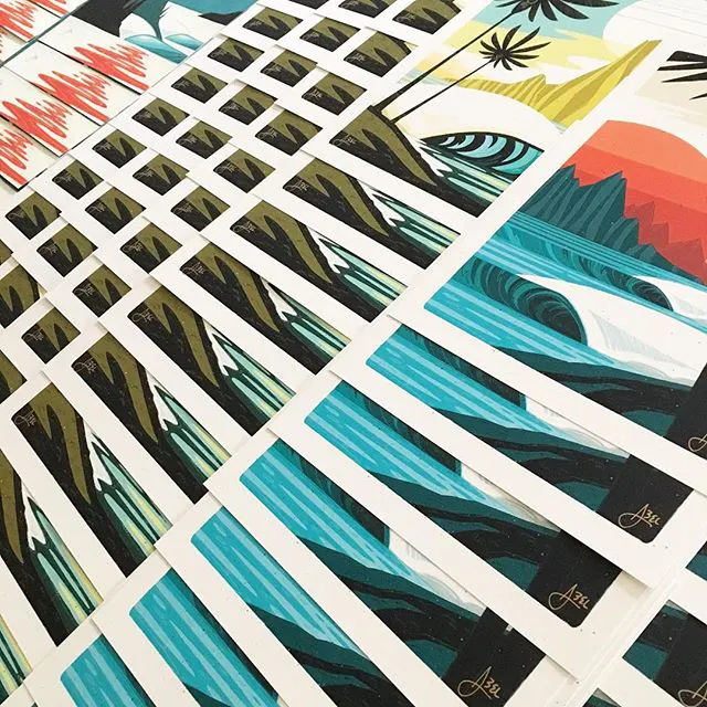 Custom art prints fanned out in rows with beach-inspired scenes in shades of blue, yellow and orange.
