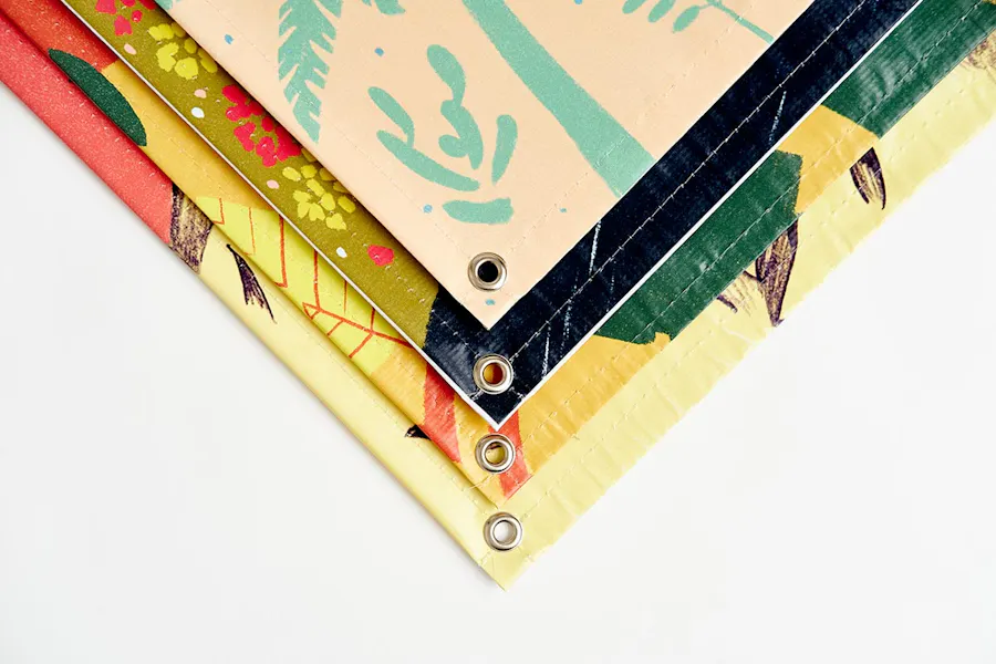 The corners of four custom banners tiered on top of each other with grommets in each one.