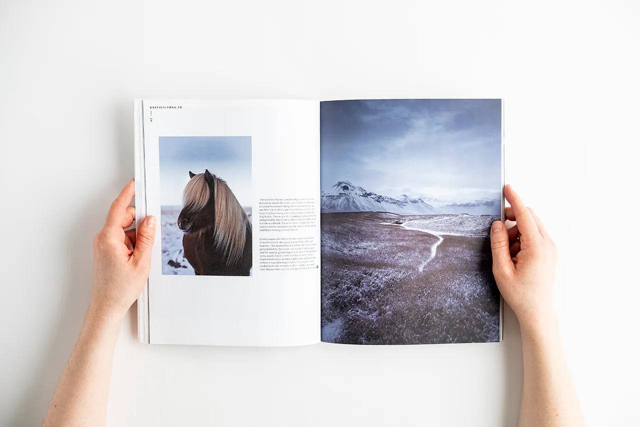 Two hands holding open a photography magazine to images of a horse and a mountain landscape in winter.