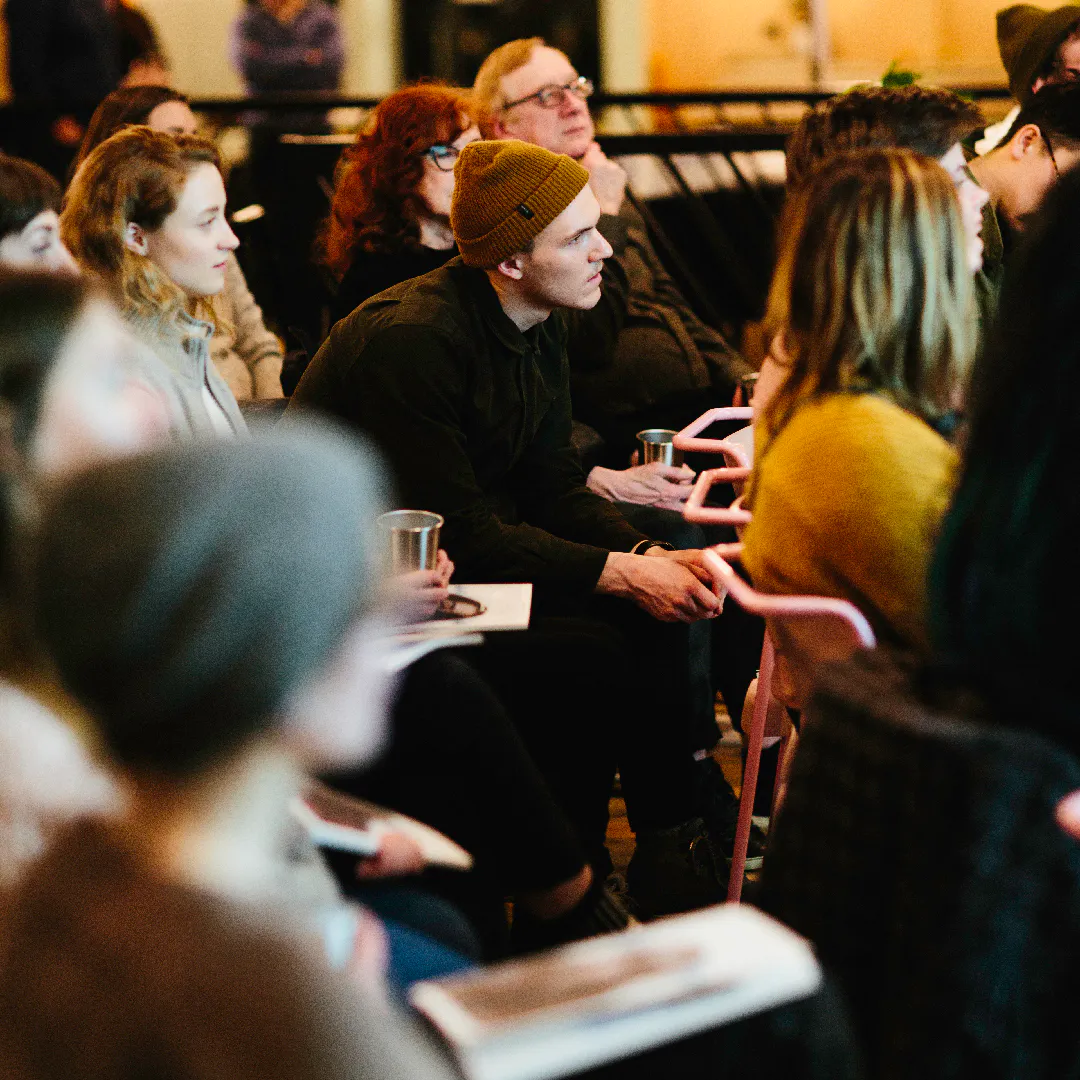 An audience sitting in chairs in rows with a Northerly photography magazine in their laps listening to a speaker.