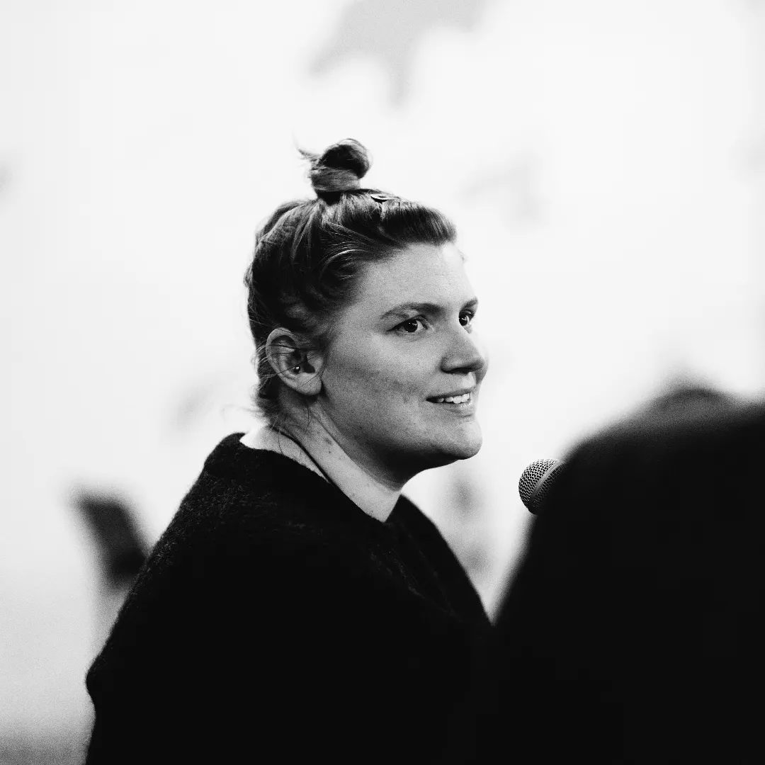 A woman with a top knot speaking into a microphone during a presentation.