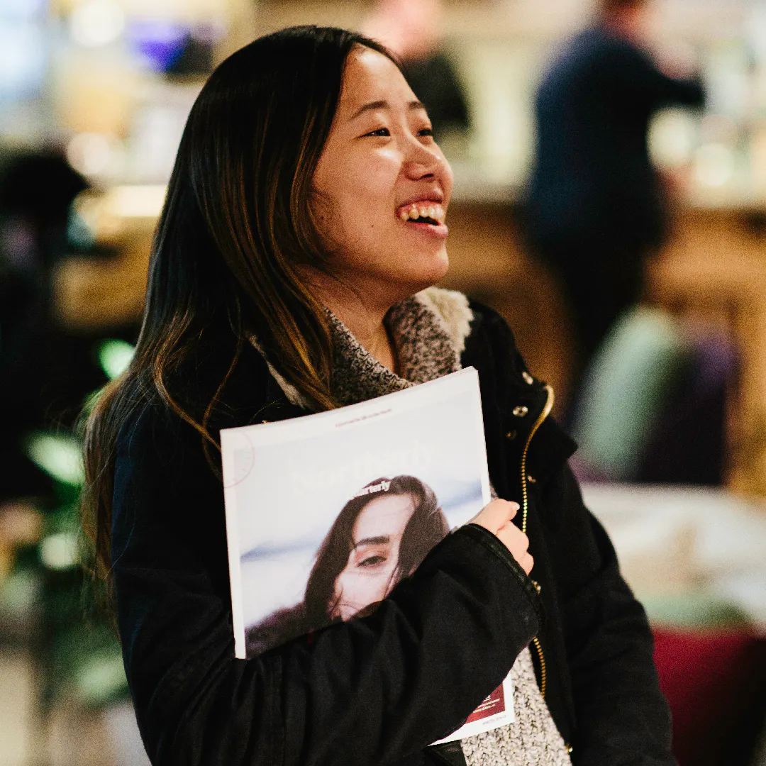 A woman with dark hair smiling and holding a Northerly photography magazine under her arm.