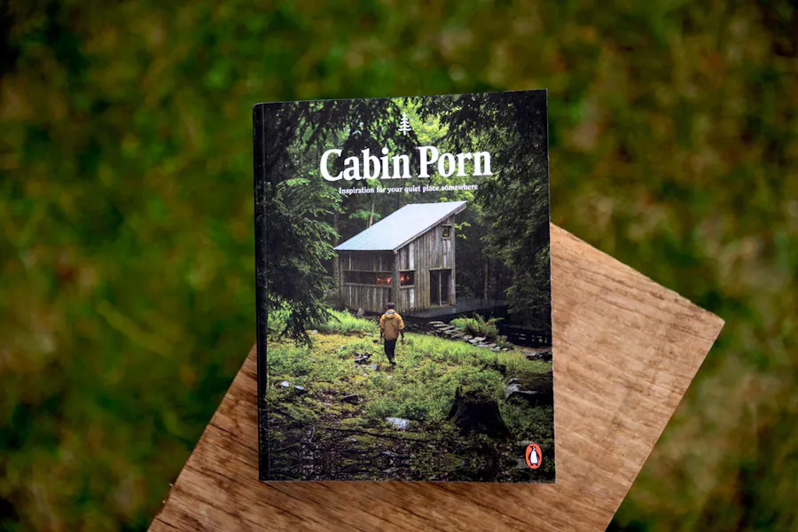 A photography magazine laying on a wooden plant with Cabin Porn in white text and an image of a cabin on the cover.