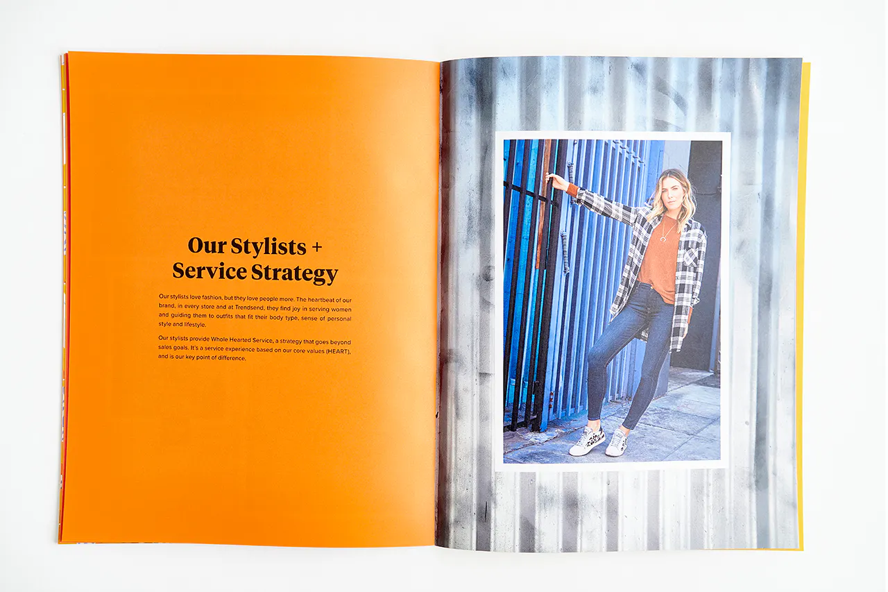 An Evereve brand book laying open to an image of a woman in a plaid shirt and details about stylists and services.