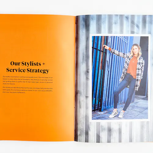 An Evereve brand book laying open to an image of a woman in a plaid shirt and details about stylists and services.